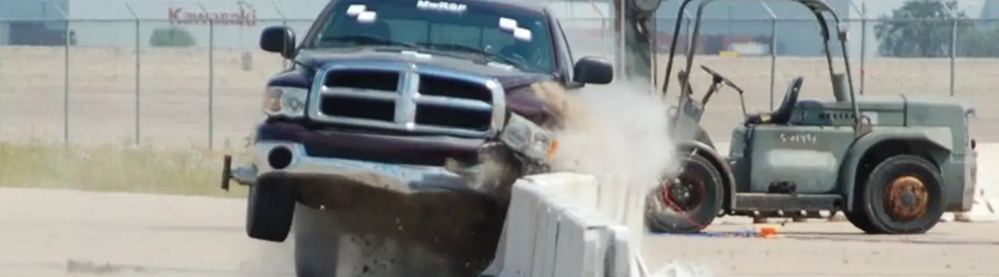 Workers installing safety barriers on a road construction site to prevent vehicle collisions.