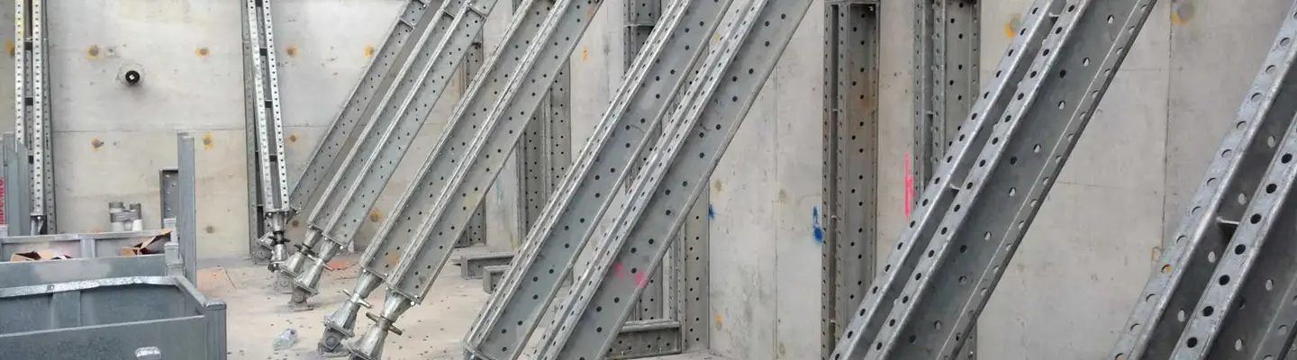 Modular Props are anchored to a concrete retaining wall, providing temporary structural support during construction.