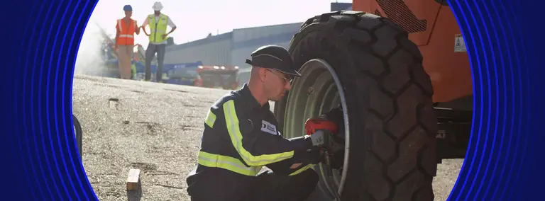 United Rentals employee working on a wheel for a boom lift
