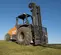 Front angled view of an orange and black CASE forklift with straight mast outdoors on grassy terrain with an open cabin.