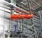 Side view of an orange and gray Skyjack scissor lift in a warehouse with an operator on platform inspecting equipment.