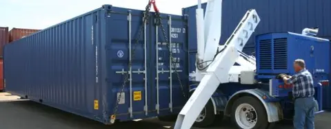 man delivering a blue shipping container with a small crane