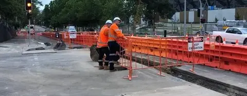 Safety barriers and fencing installed along a light rail track to protect pedestrians and secure the construction area.