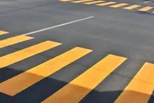 Freshly paved asphalt road with clear lane markings, representing safe road conditions supported by temporary barriers.