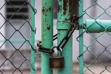 Lock gate secured with chains and signage, restricting access to a hazardous or restricted worksite area.