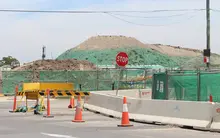 Various dependable construction equipment positioned along a roadway, supporting barrier installation and roadwork operations.